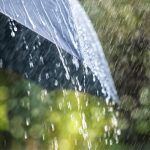 Rain drops falling from a black umbrella concept for bad weather, winter or protection